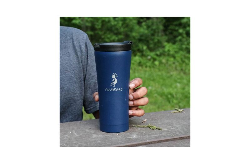 Vaso térmico metálico 16 onzas azul Aquapelli Chef Craft, sostenido por una mano sobre una superficie de madera al aire libre