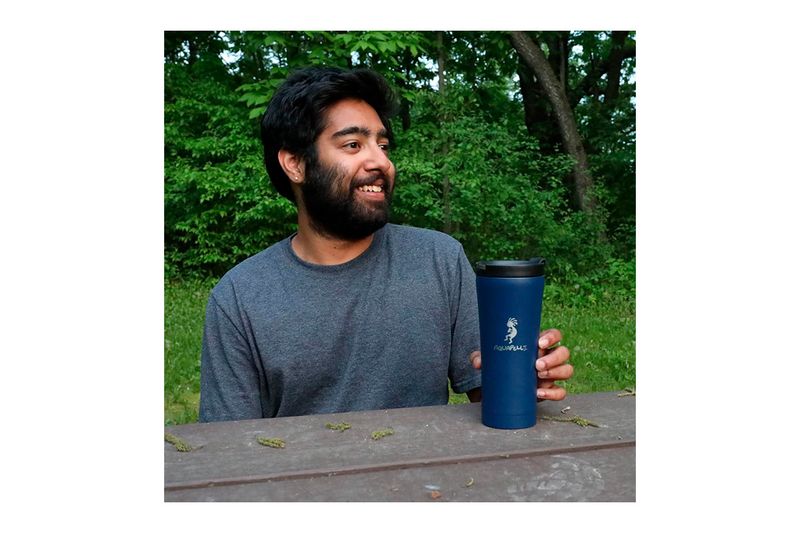 Vaso térmico metálico 16 onzas azul Aquapelli Chef Craft, sostenido por un hombre en un entorno natural al aire libre