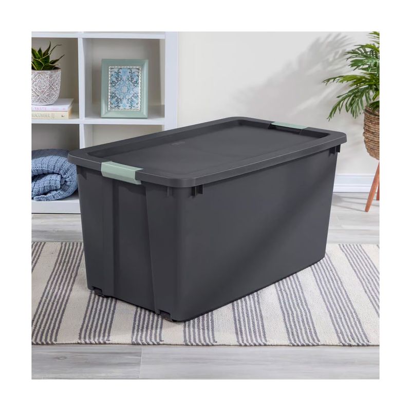 Caja organizadora de 45 galones con tapa gris oscuro Sterilite, ubicada en una habitación sobre una alfombra a rayas