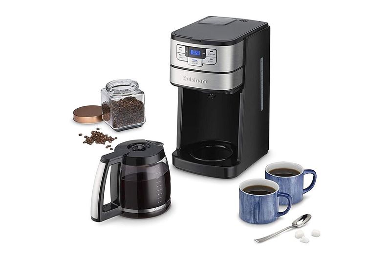 Cafetera moledora automática 12 tazas negro Cuisinart, junto a jarra con café, granos en frasco y dos tazas azules