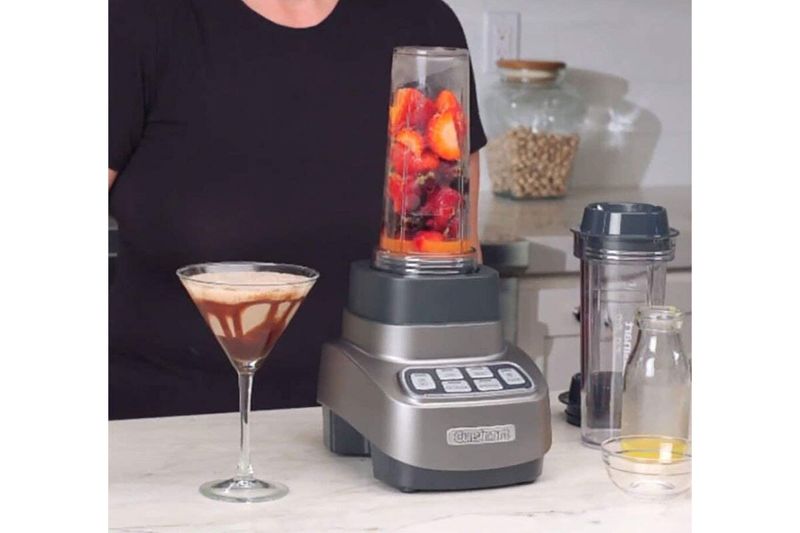Juego licuadora procesador Velocity Ultra 1 HP 7 piezas Cuisinart, en uso con fresas y vaso de bebida al lado