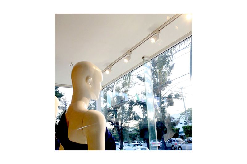 Riel para luminaria blanco de 2 metros Tecnolite, instalado en techo con tres focos orientables iluminando maniquíes