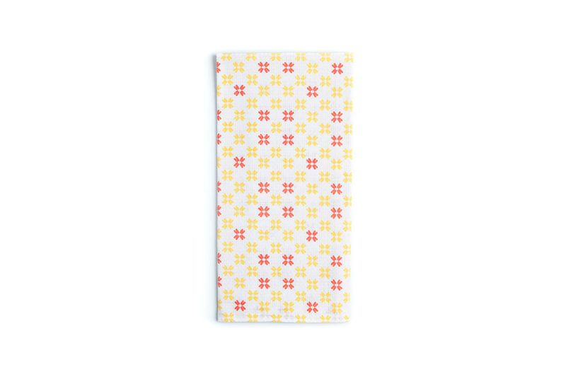 Toalla para cocina blanca con estampado naranja Sttelli, vista cenital del tejido extendido con diseño de flores