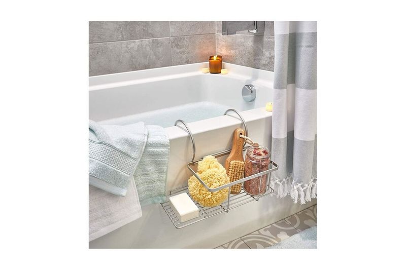 Bandeja organizadora de baño colgante pequeña plata mate iDesign, instalada en el borde de una tina con accesorios