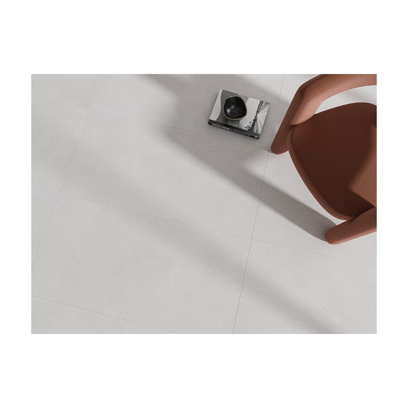 Porcelanato 60x120 Shade White Mate Rect Ibero, vista cenital del piso instalado con una silla color café y un libro