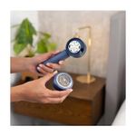 Removedor de pelusas recargable Black+Decker, manos sosteniendo el equipo azul con la rejilla protectora desmontada