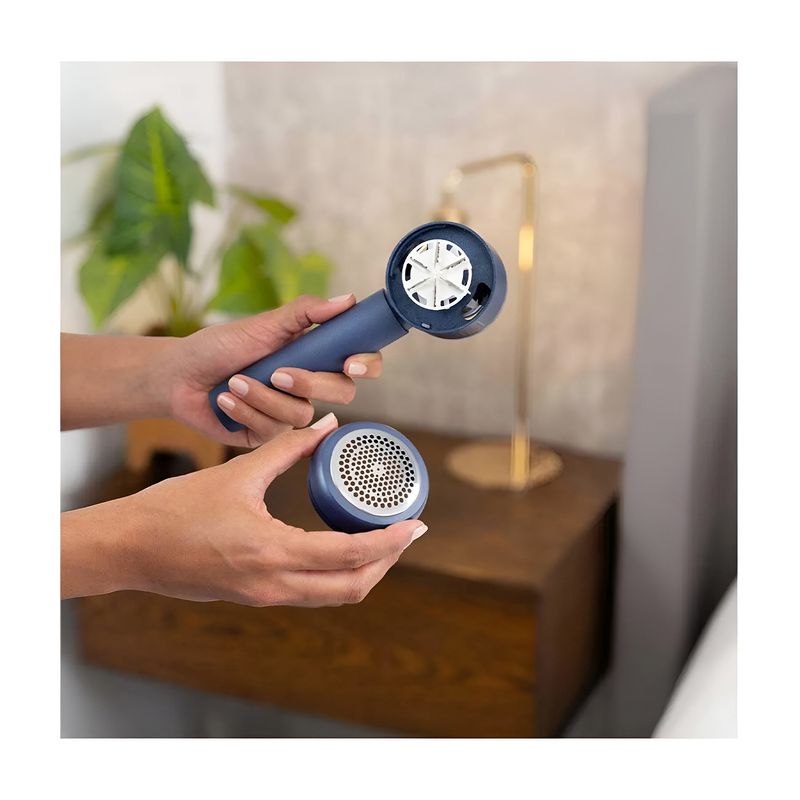 Removedor de pelusas recargable Black+Decker, manos sosteniendo el equipo azul con la rejilla protectora desmontada