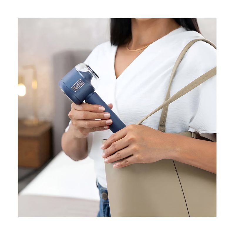 Removedor de pelusas recargable Black+Decker, persona sosteniendo el aparato azul junto a un bolso color beige