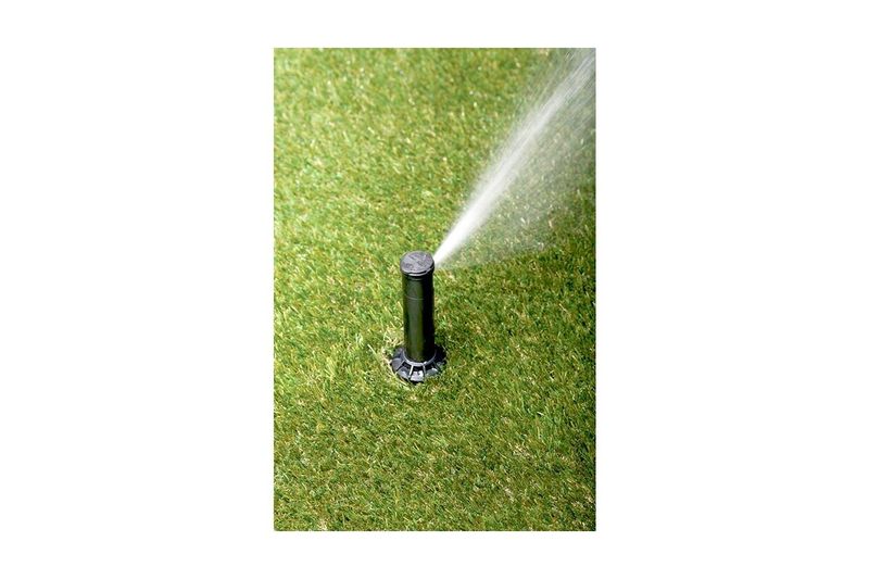 Aspersor para jardín ajustable 1/2 pulgadas Rain Bird, instalado en césped verde emitiendo chorro de agua
