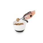 Cuchara para helados y galletas negro acero inox OXO, mano usando el utensilio para sacar masa de un bol blanco