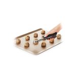 Cuchara para helados y galletas negro acero inox OXO, mano utilizando el utensilio para colocar masa en una bandeja