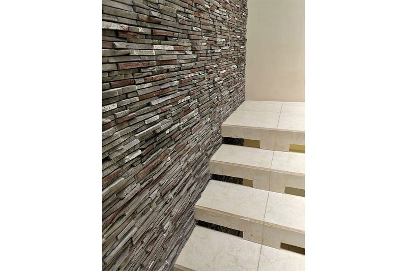 Caja piedra ecológica Ekos plomo Pirka Stone, instalada en una pared junto a unas escaleras de color blanco