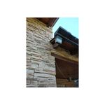 Caja piedra ecológica Kamba arena mate Pirka Stone, instalada en pared exterior con techo de madera y lámpara