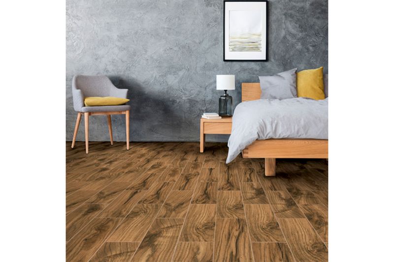 Baldosa 20 x 60 madera olivo brillante Hispacensa, instalada en piso de habitación con cama y silla