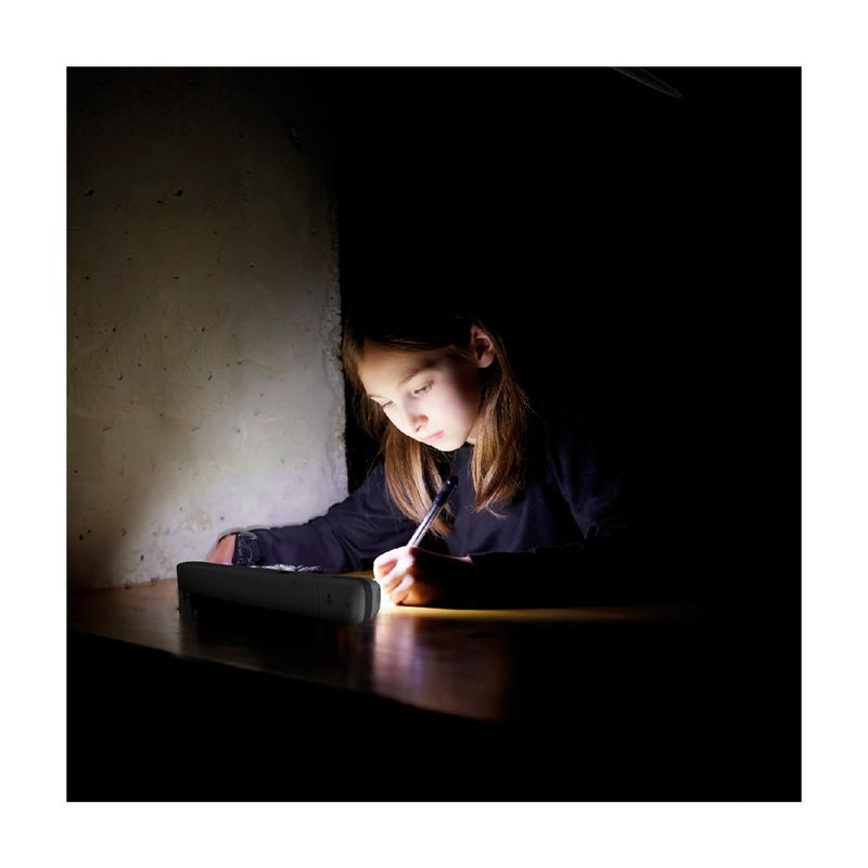 Luminaria de emergencia recargable 5 W 6500 K Sylvania, encendida sobre una mesa iluminando a una niña que escribe
