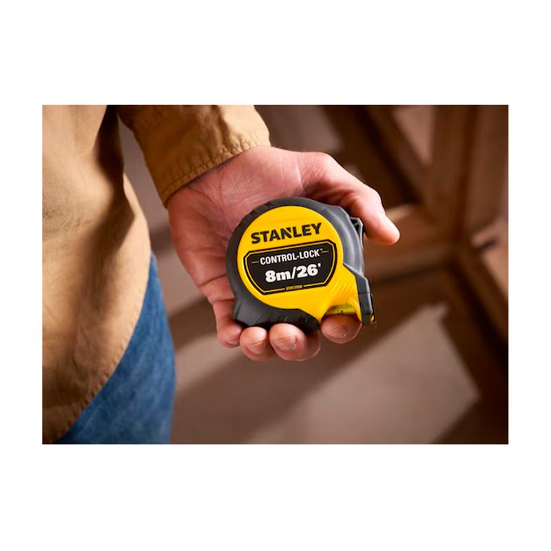 Cinta métrica Control Lock Stanley de 1 pulgada x 8 metros, sostenida por una mano mostrando el frente amarillo y negro