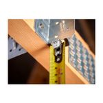 Cinta métrica Control Lock Stanley de 1 pulgada x 8 metros, en uso midiendo la esquina de una estructura de madera y metal