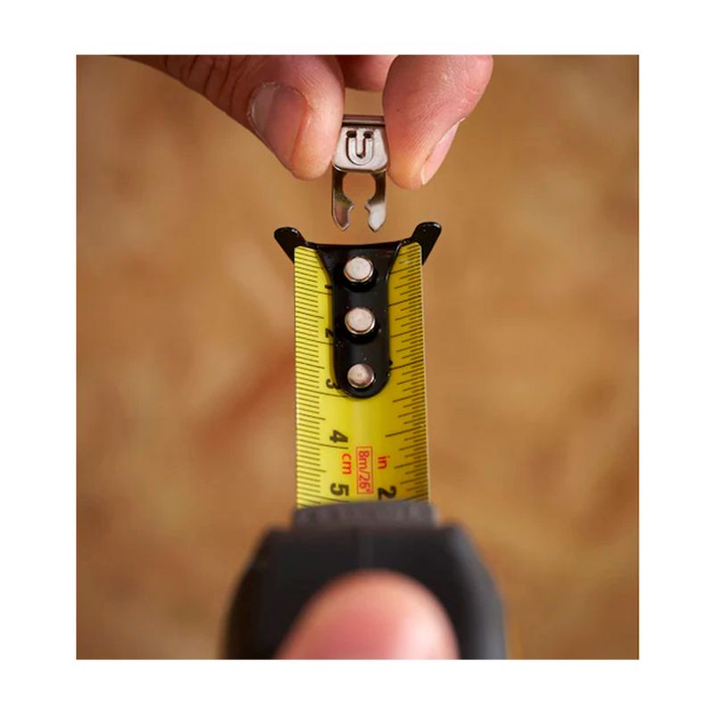 Cinta métrica Control Lock Stanley de 1 pulgada x 8 mts, detalle del gancho metálico siendo colocado en la cinta amarilla