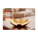 Centro decorativo 34.5 x 34.5 x 9 cm dorado Concepts, ambientado sobre una mesa de madera en una sala con sofá