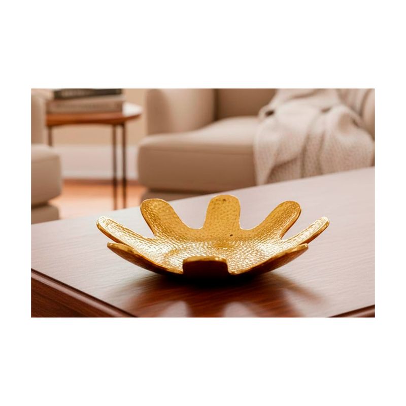 Centro decorativo 34.5 x 34.5 x 9 cm dorado Concepts, ambientado sobre una mesa de madera en una sala con sofá