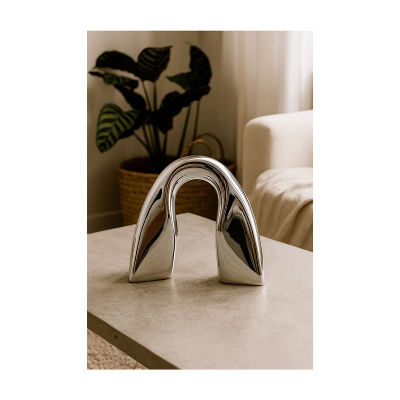 Arco decorativo 23.5 x 11 x 23 cm Concepts, pieza plateada brillante ubicada sobre una mesa en ambiente decorado