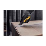 Navaja plegable DeWALT de 31 mm, siendo utilizada por una mano con guante para cortar una caja de cartón