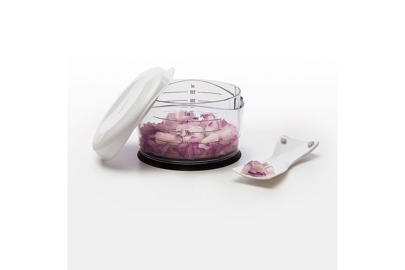 Picador de alimentos pequeño crema Oxo, recipiente transparente con cebolla picada, tapa abierta y cuchara pequeña