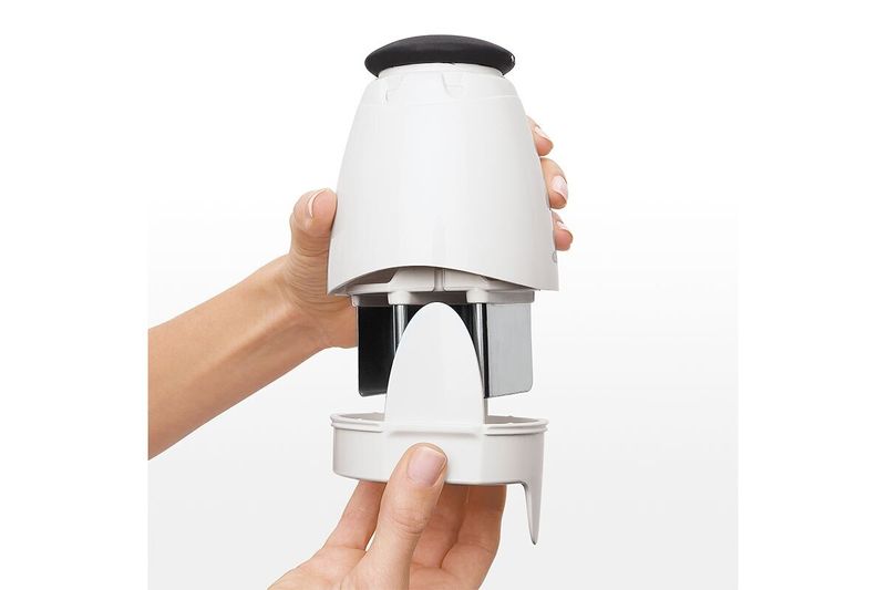 Picador de alimentos pequeño crema OXO, manos separando el recipiente para mostrar las cuchillas internas de metal