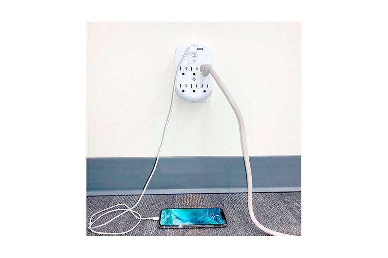 Adaptador smart con supresor + 2 puertos USB 6 salidas 2.4 amp 120-240 V Westinghouse, instalado en pared cargando un celular