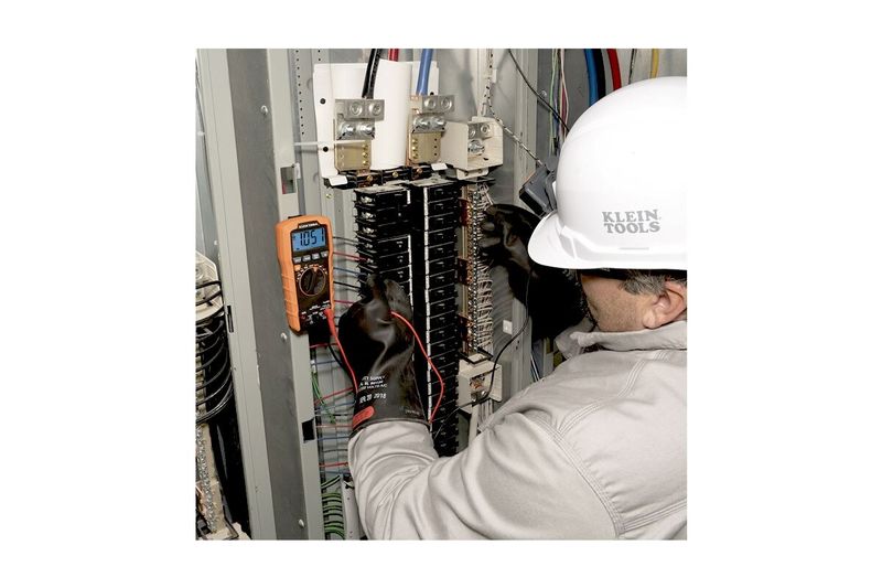 Multímetro digital autorango Klein Tools CAT III, técnico usando el equipo para medir un tablero eléctrico industrial