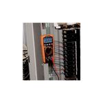 Multímetro digital autorango Klein Tools CAT III, en uso midiendo un panel eléctrico con cables conectados