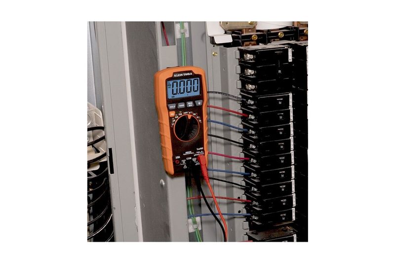 Multímetro digital autorango Klein Tools CAT III, en uso midiendo un panel eléctrico con cables conectados