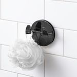 Gancho para baño autoadhesivo doble negro mate Interdesign, instalado en pared de azulejos blancos con una esponja blanca