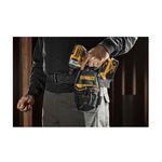 Bolso porta taladro DeWALT de 7 bolsillos, colocado en el cinturón de un usuario sosteniendo un taladro amarillo