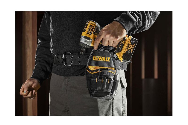 Bolso porta taladro DeWALT de 7 bolsillos, colocado en el cinturón de un usuario sosteniendo un taladro amarillo