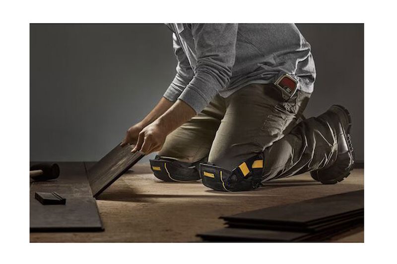 Rodilleras profesionales acolchadas DeWALT, vistas puestas en un trabajador arrodillado manipulando madera