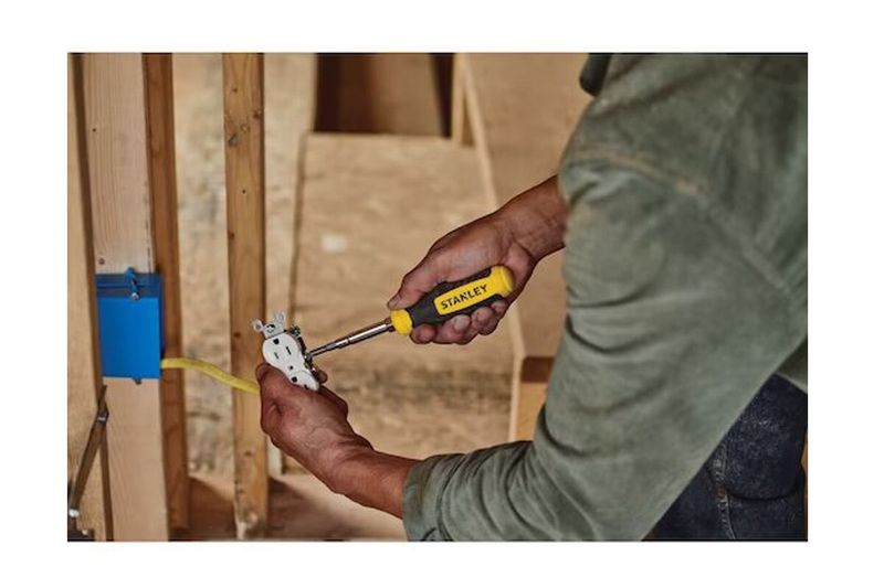 Desarmador intercambiable 6 en 1 Stanley, persona utilizándolo para ajustar un tomacorriente eléctrico en una pared