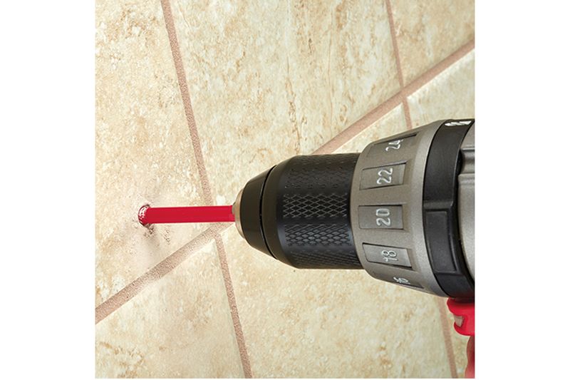 Broca diamantada para cerámica 1 pulgada Milwaukee, perforando una superficie de azulejos beige con un taladro