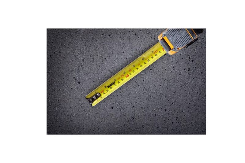 Cinta métrica ToughSeries de 8 m / 26 ft con luz LED DeWALT, extendida sobre una superficie de asfalto gris