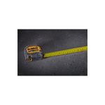 Cinta métrica ToughSeries de 8 m/26 ft con luz LED DeWALT, extendida sobre superficie oscura