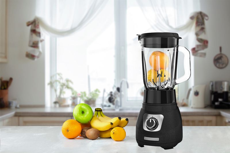 Licuadora Cyclone 2 velocidades vaso vidrio color negra Black + Decker, con frutas dentro y junto al equipo en cocina