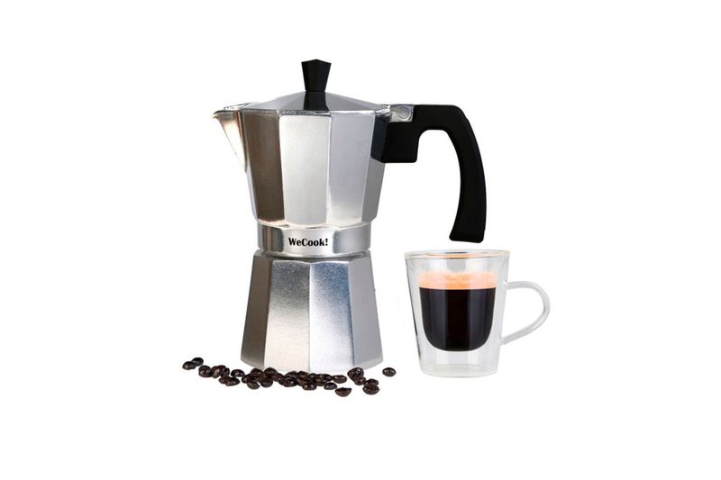 Cafetera italiana plateada aluminio 9 tazas Sinsa, junto a una taza de vidrio con café y granos esparcidos