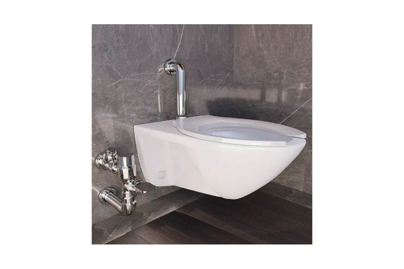 Fluxómetro pedal WC 32-38 mm codo 4.8 l cromo Helvex, instalado en sanitario blanco suspendido sobre pared de mármol