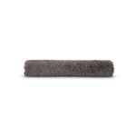 Alfombra para baño Lush gris Sttelli, enrollada mostrando la textura suave y esponjosa del material