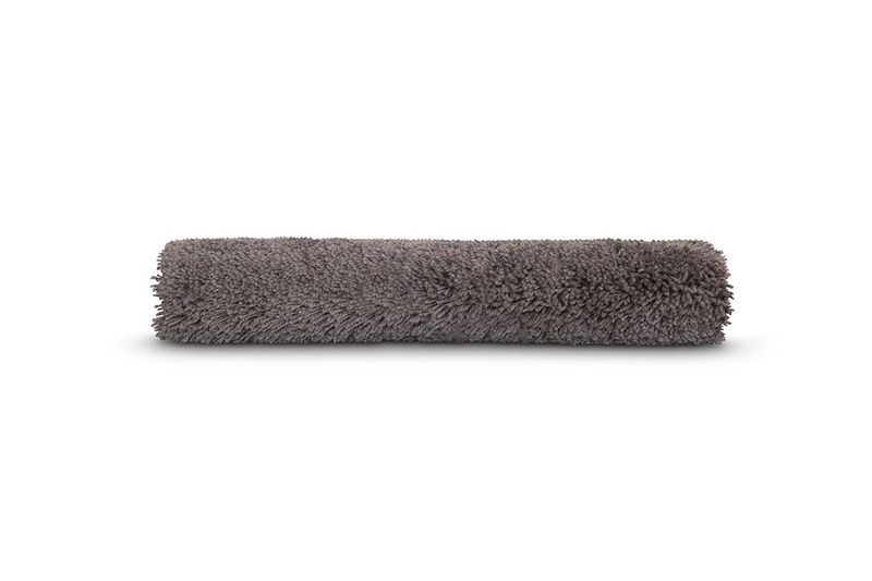 Alfombra para baño Lush gris Sttelli, enrollada mostrando la textura suave y esponjosa del material