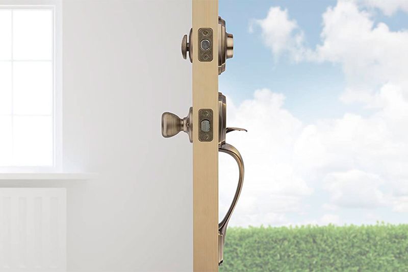 Cerradura pichel Belleview llave/mariposa bronce antiguo Kwikset, instalada en puerta abierta vista lateral del perfil