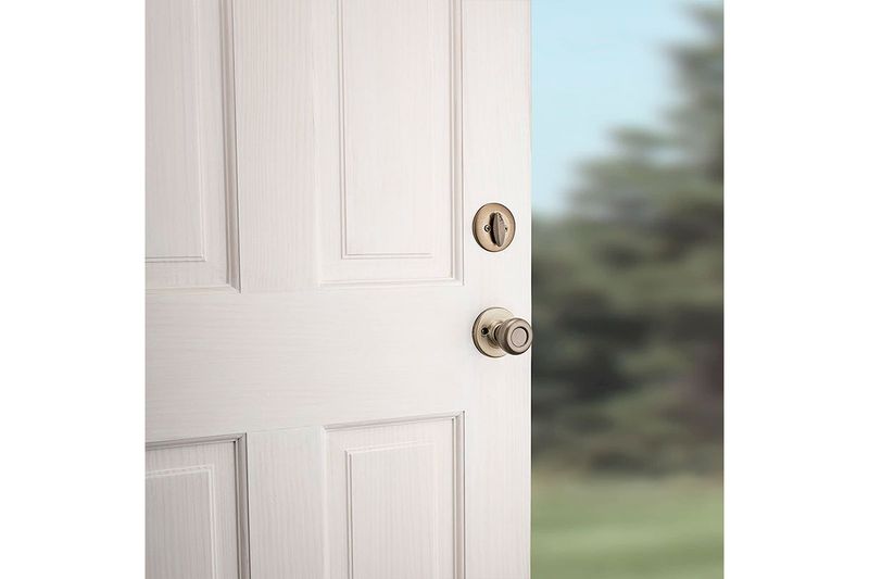 Cerradura pichel Belleview llave/mariposa bronce antiguo Kwikset, instalada en puerta blanca con vista lateral