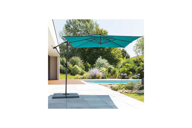 Sombrilla Manoa Peacck de 2.5 m Hespéride, abierta en color turquesa instalada en patio junto a piscina y jardín