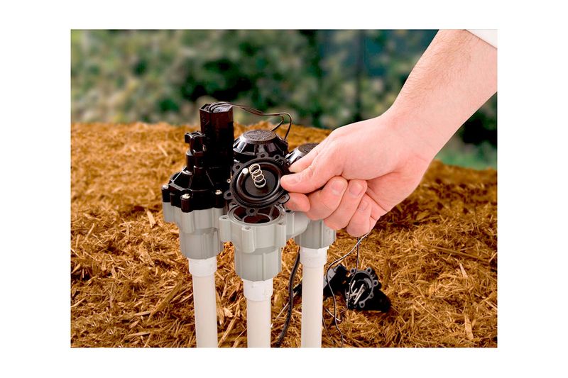 Kit de reemplazo de diafragma Rain Bird, mano instalando el diafragma de caucho negro en una válvula de riego blanca