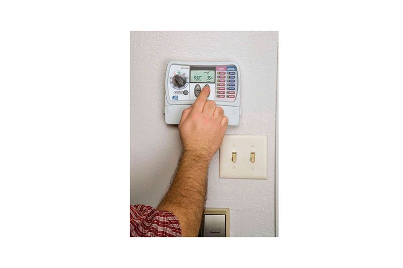 Temporizador de riego 6 zonas Rain Bird, mano de persona ajustando la configuración en el panel de control instalado